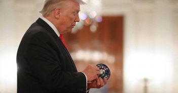 President donald trump holds a coin in his hand.
