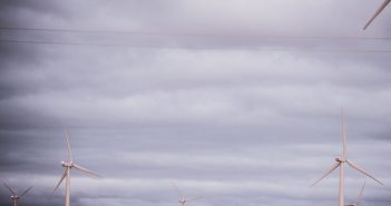 A group of wind turbines under a cloudy sky.