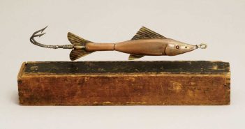 A fish lure on top of a wooden box.