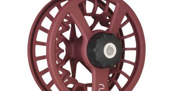 A maroon fly reel with a black handle.