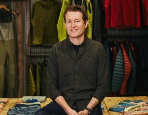 A man sitting in front of a rack of clothes.