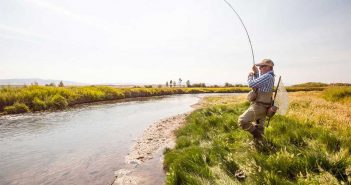 A man is fly fishing on a river.