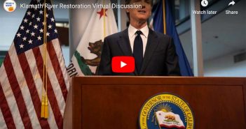 A man is standing at a podium in front of an american flag.