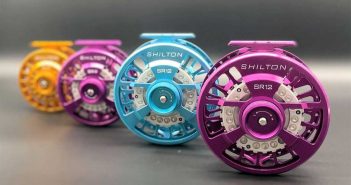 A row of colorful fly reels on a black surface.