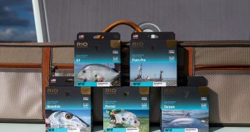 Four packages of fishing flies sitting on a suitcase.