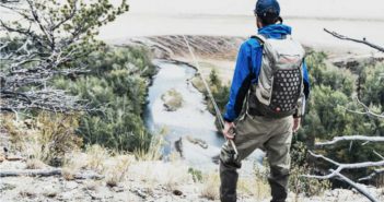 A man is standing on a hill overlooking a river.