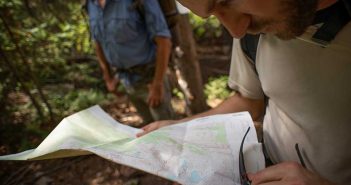 A man looking at a map in the woods.