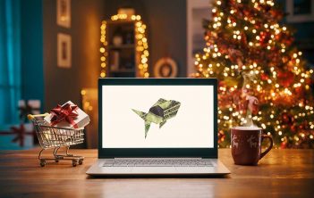 A laptop on a table with a christmas tree in the background.