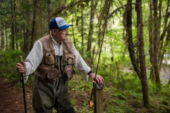 A man with a fishing pole in the woods.