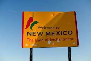 A sign that says welcome to new mexico the land of enchantment.