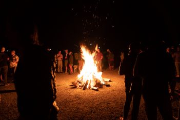 A group of people standing around a bonfire at night.