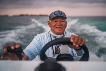 An older man driving a boat in the ocean.