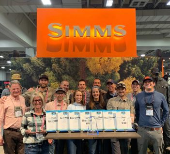 A group of people standing in front of a simms sign.