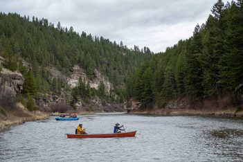 Three people in a canoe on a river.