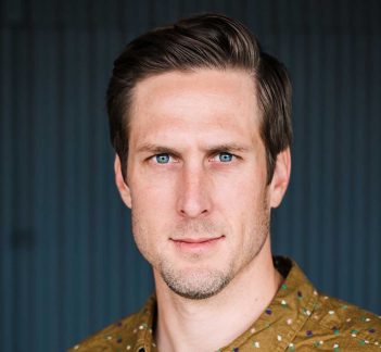 A man in a yellow shirt with blue eyes.