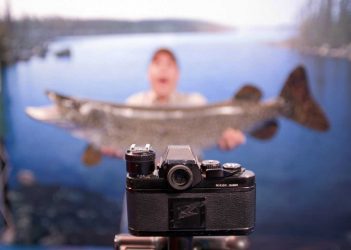 A man is holding a fish in front of a camera.