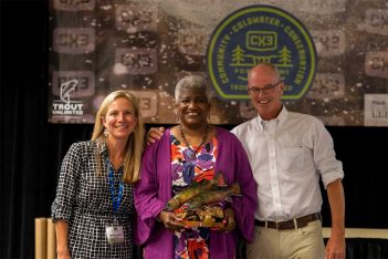 Three people posing for a photo with an award.