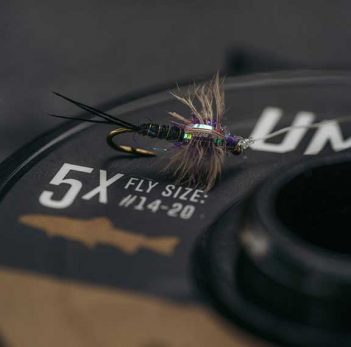 A fly is sitting on top of a reel.