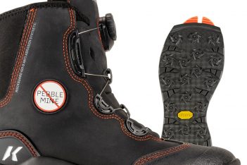 A pair of black ski boots with orange soles.