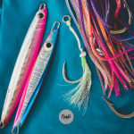 A group of colorful fishing lures laying on top of a blue cloth.