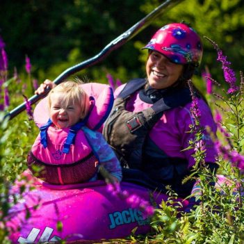A woman with a baby in a pink kayak.