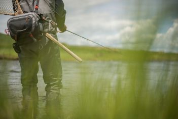 A man is holding a fly fishing rod in the water.