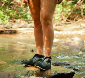 A woman standing on a rock next to a stream.