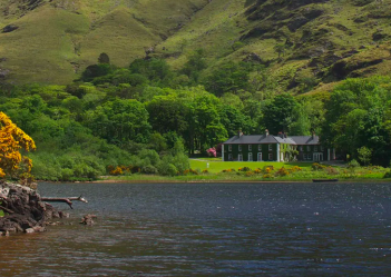 A house sits on the side of a lake in ireland.