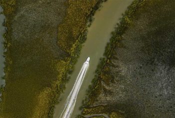 An aerial view of a boat traveling down a river.