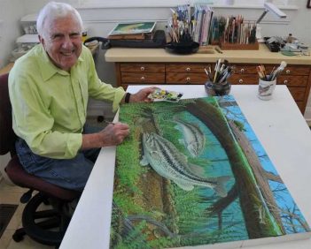 A man sitting in front of a painting of a fish.