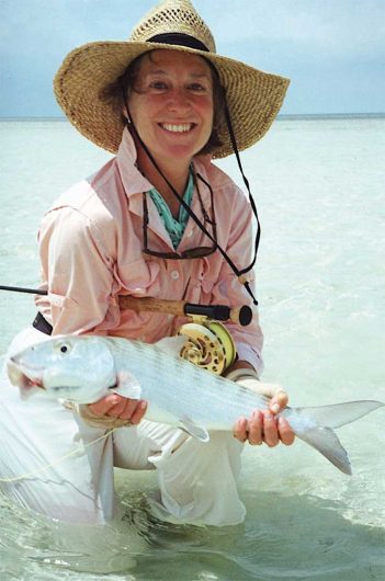 A woman in a hat holding a fish in the water.