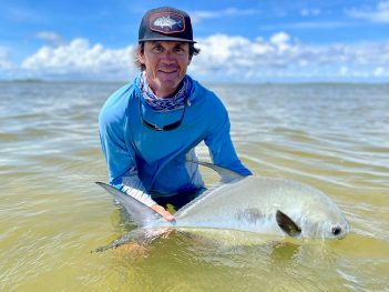 A man holding a fish in the water.