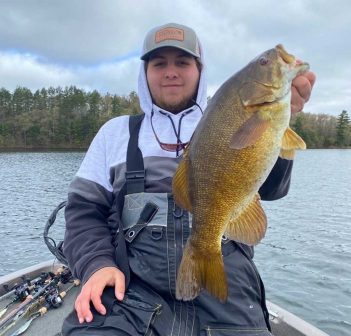 A man holding up a large bass on a boat.