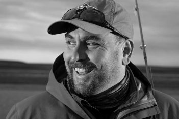 A black and white photo of a man holding a fishing rod.