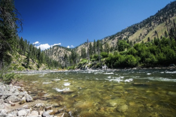 A river surrounded by mountains and trees.