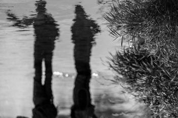 A black and white photo of two people standing in water.
