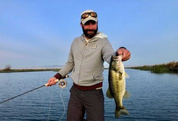 A man holding up a large bass on a lake.