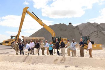 A group of people standing in front of a pile of sand.