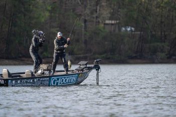 Two men are fishing on a boat in a lake.