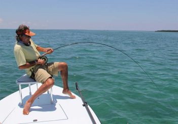 A man is fishing on a boat in the ocean.