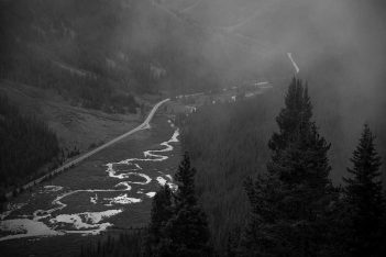 A black and white photo of a river in the mountains.