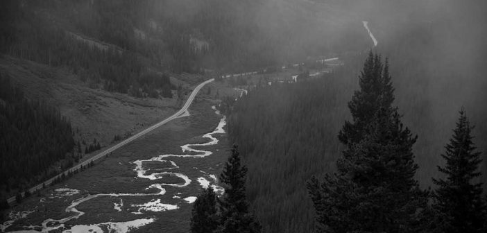 A black and white photo of a river in the mountains.