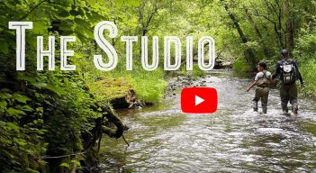 Two people walking through a stream with the words the studio.