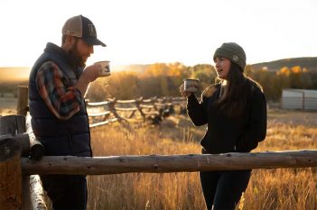 A man and woman drinking coffee in a field.