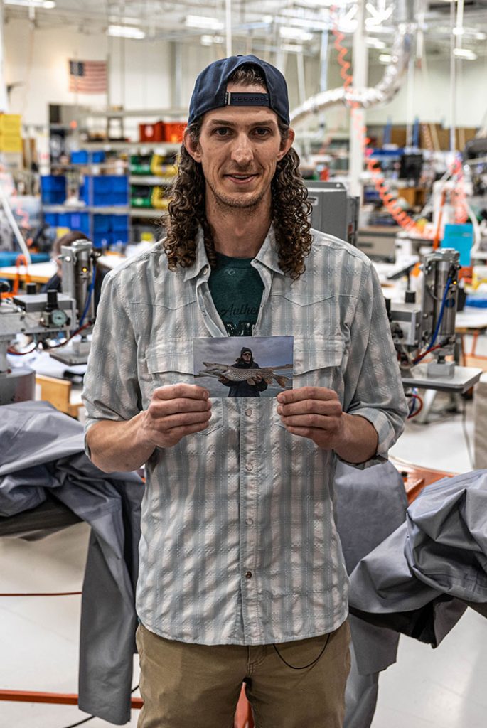 A man holding a photo in a factory.