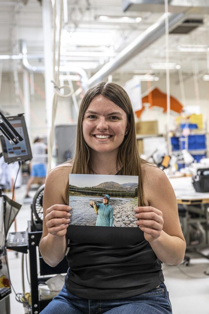 A woman holding up a photo in a factory.
