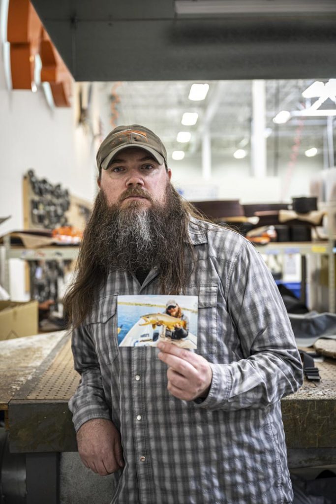 A man with a long beard holding a picture in a workshop.
