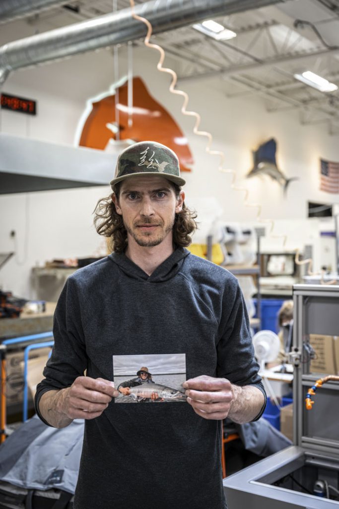 A man holding up a photo in a factory.