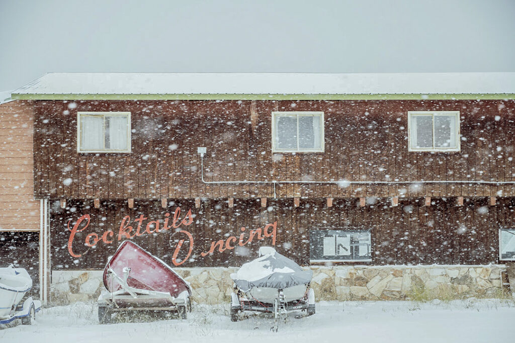 A boat is parked in front of a building in the snow.