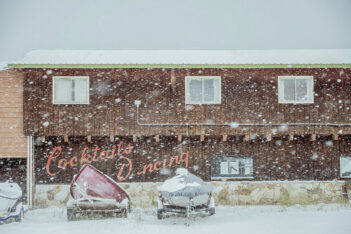 A boat is parked in front of a building in the snow.